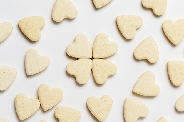 Saint Valentine day minimalistic greeting card, scattered heart-shaped sweet little cookies on white background, flat lay