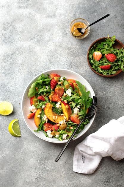 Salad bowl with arugula, strawberry, cottage cheese, nectarine and peanut paste. healthy eating concept