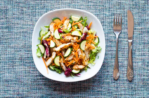 Salad of chicken breast with zucchini and cherry tomatoes on a wooden background