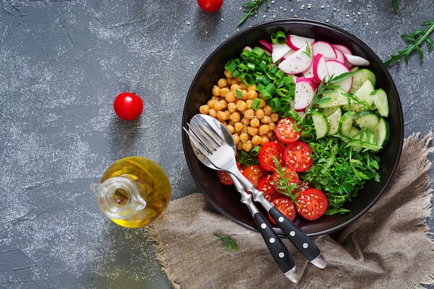 Salad of chickpeas, tomatoes, cucumbers, radish and greens. Dietary food. Vegan salad. Top view. Flat lay. Buddha bowl