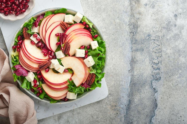 Salad Fresh fruit green salad with feta cheese apple pomegranate pecan and lettuce on white plate Idea for healthy delicious winter Christmas salad Healthy balanced eating Top view