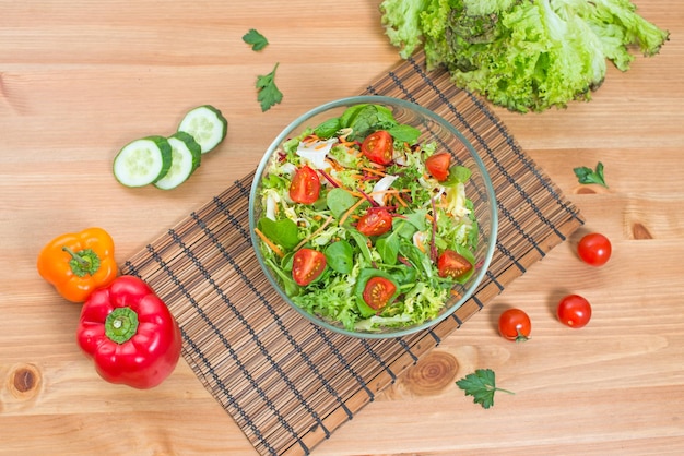 Salad of fresh vegetables and green on wooden background top view