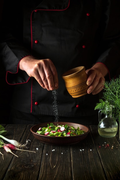 Salad of fresh vegetables must be salted The cook throws salt into a plate with a delicious salad