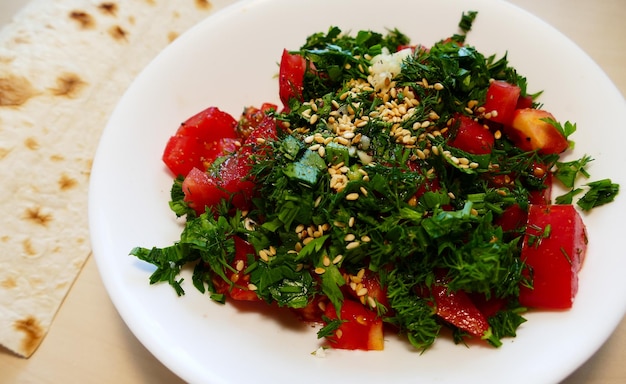 Salad of fresh vegetables with herbs and sesame seeds served on a plate with unleavened bread