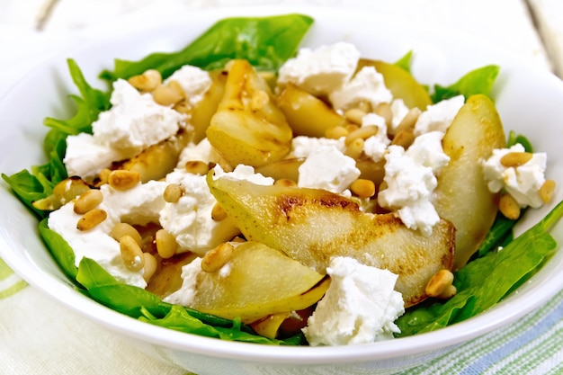 Salad from pear and spinach with feta in dish on board