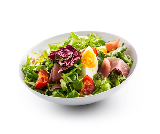 Salad Isolated on White. a bowl of fresh lettuce salad with tomatoes eggs prosciutto over white.