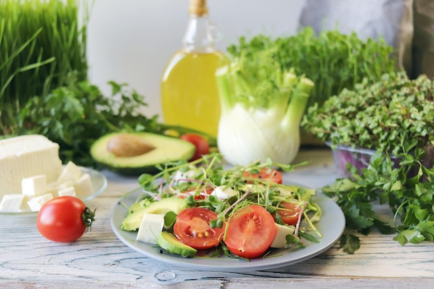 Salad of microgreens avocado tomatoes cheese and arugula on a plate