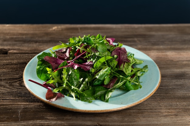 Salad mix of fresh herbs in a plate on a wooden table