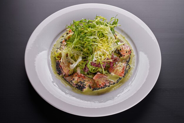 Salad mix with lightly salted salmon and sauce, on a white plate