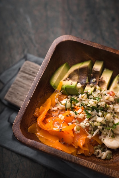 Salad of pumpkin avocado banana in a wooden bowl top view