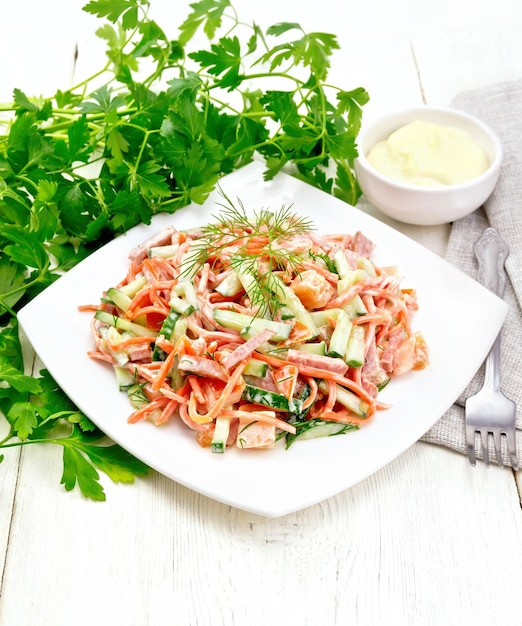 Salad of sausage and spicy carrots with mayonnaise on wooden table