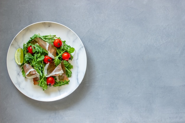 Salad with arugula, tomatoes and prosciutto.