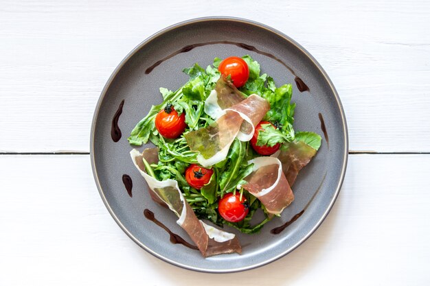 Salad with arugula, tomatoes and prosciutto.