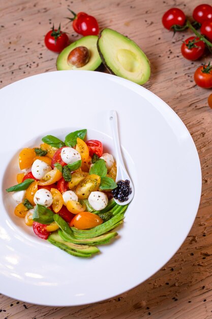 salad with avacado mozzarella and tomatoes in a white plate