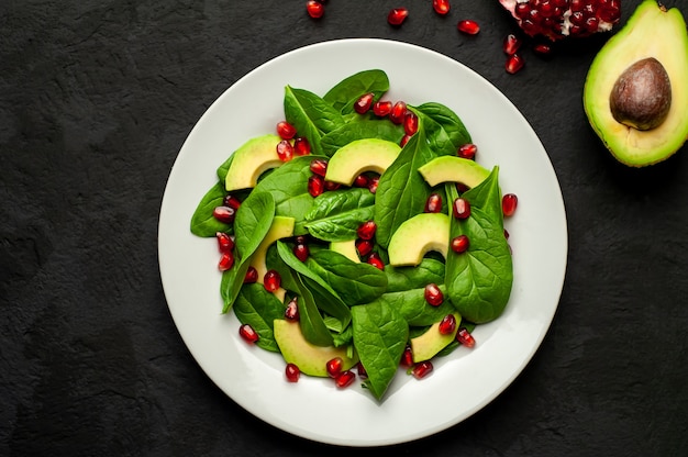 salad with avocado, arugula, spinach, pomegranate, seeds on a stone background