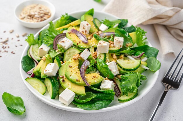 Salad with avocado closeup on a gray background Vegetarian salad with vegetables feta and seeds Side view