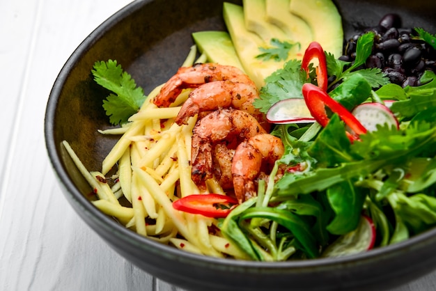 Salad with avocado and shrimps in bowl, top view. Healthy food