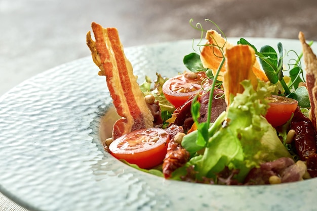 Salad with bacon and beef in a plate. Close-up, selective focus.