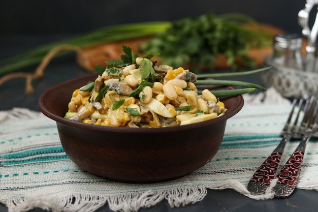 Salad with beans, corn, eggs and champignons in a brown bowl