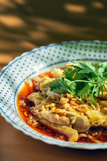 Salad with boiled chicken, cilantro, peanuts in hot soy sauce. Chinese cuisine.