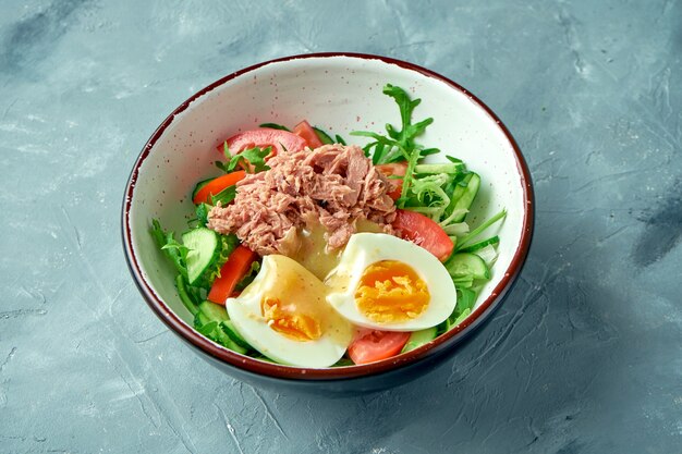 Salad with canned tuna, egg and hollandaise sauce on a gray background