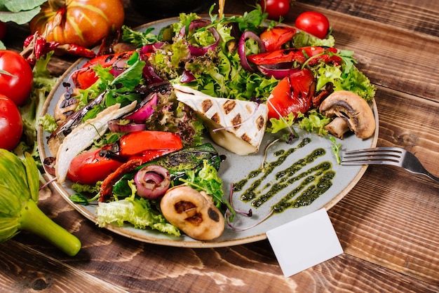 Salad with cheese, mushrooms and vegetables on wooden background