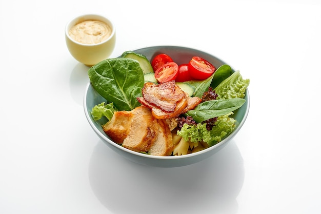 Salad with chicken bacon and tomatoes in a bowl on a white background