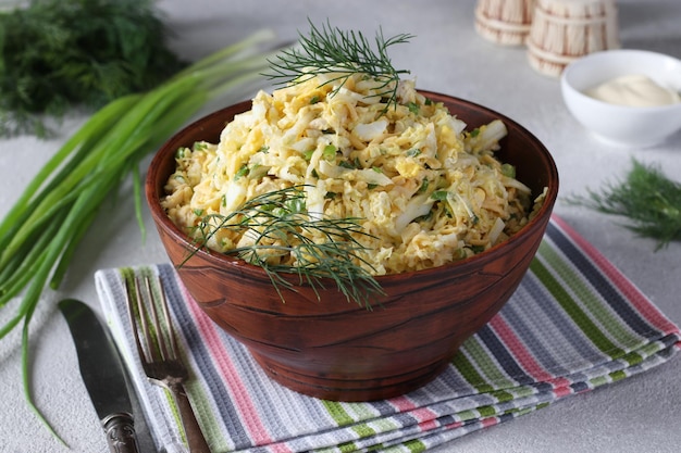 Salad with chicken Chinese cabbage boiled eggs and cheese in a brown salad bowl on a gray background