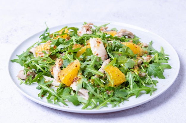 Salad with chicken oranges and arugula Dressing with olive oil and grain mustard Closeup