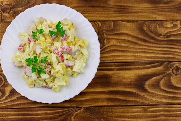 Photo salad with crab sticks sweet corn chinese cabbage eggs and mayonnaise on wooden table