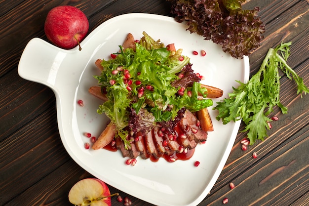 Salad with duck brisket suvid on a wooden table