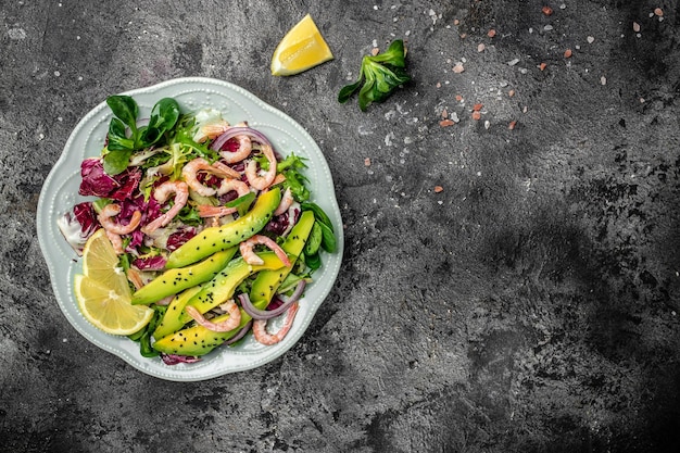 Photo salad with fresh avocado shrimps lettuce green mix and olive oil lemon dressing healthy food delicious breakfast or snack clean eating dieting vegan food concept top view