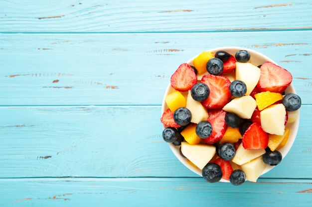 Salad with fresh fruits and berries on wooden background