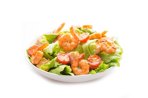 Salad with fresh leaves, shrimp, cherry tomatoes in a plate isolated on a white background.