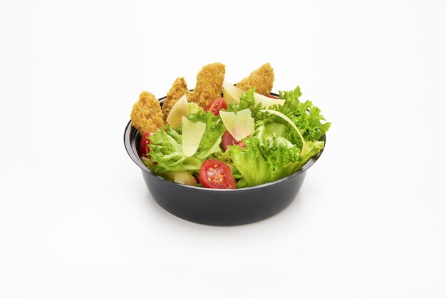 Salad with fried chicken strips and sliced parmesan cheese in a plastic take away bowl