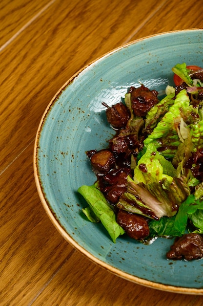 Salad with fried mushrooms, tomatoes and lettuce on a wooden table,top view