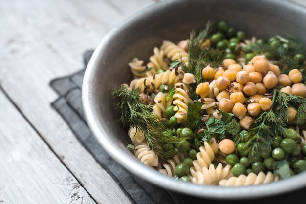 Salad with fusilli chickpeas grass in a metal bowl top view