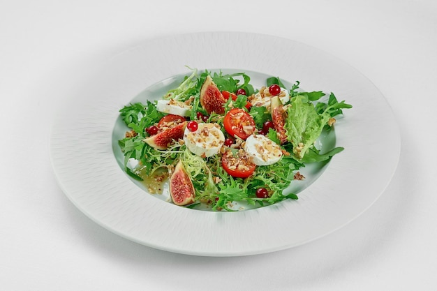 Salad with goat cheese and figs in a white plate on a white tablecloth Closeup selective focus