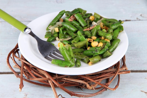 Salad with green beans ham and corn on plate on color wooden background