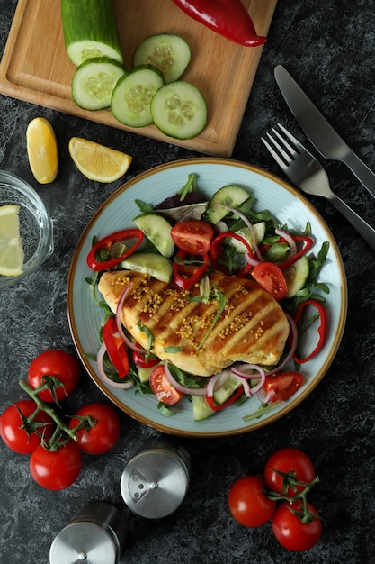 Salad with grilled chicken on black textured table