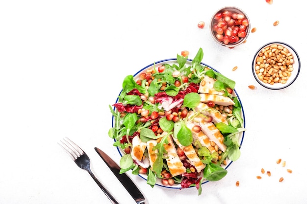 Salad with grilled chicken spinach arugula cedar nuts and pomegranate seeds Healthy food and eating concept Top view Blue background