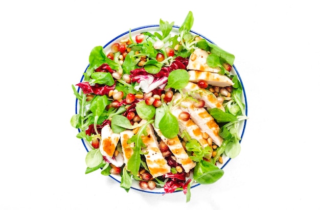 Salad with grilled chicken spinach arugula cedar nuts and pomegranate seeds Healthy food and eating concept Top view Blue background