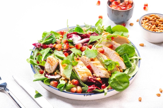 Salad with grilled chicken spinach arugula cedar nuts and pomegranate seeds Healthy food and eating concept Top view Blue background