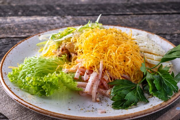 Salad with ham on a plate in rustic style.