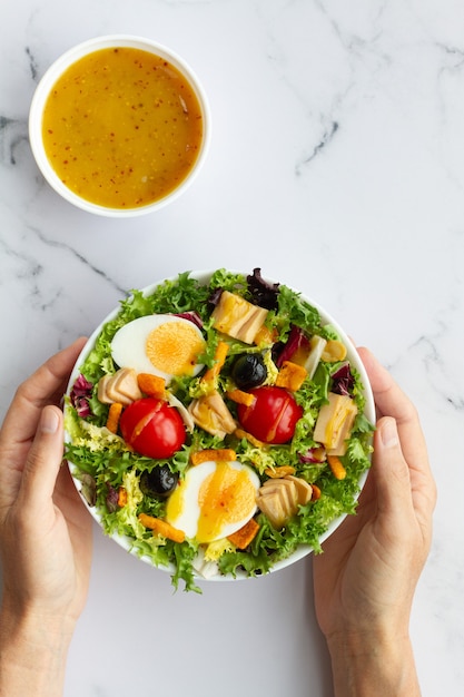 Salad with lettuce egg tuna olives and honey and mustard vinaigrette on white background