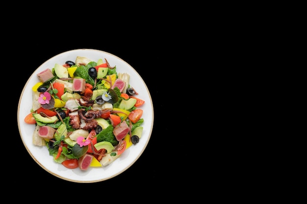 Salad with octopus tuna and vegetables on a dark background