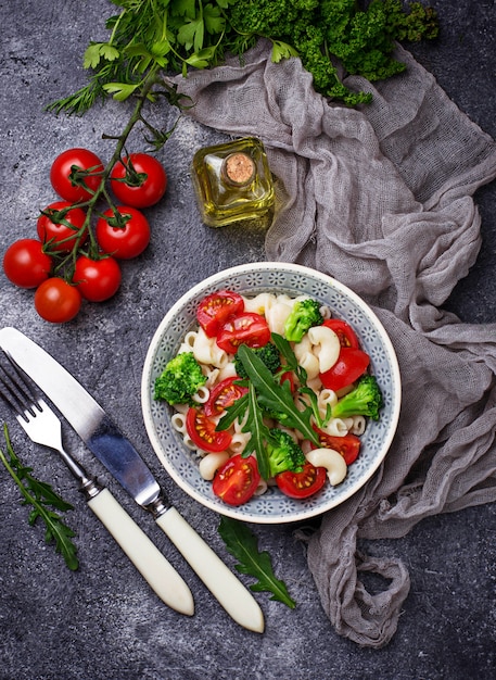 Salad with pasta, cherry tomatoes, broccoli and arugula. Vegan food