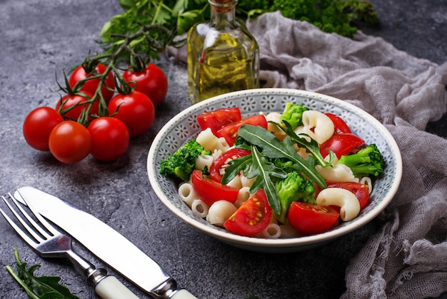 Photo salad with pasta, cherry tomatoes, broccoli and arugula. vegan food