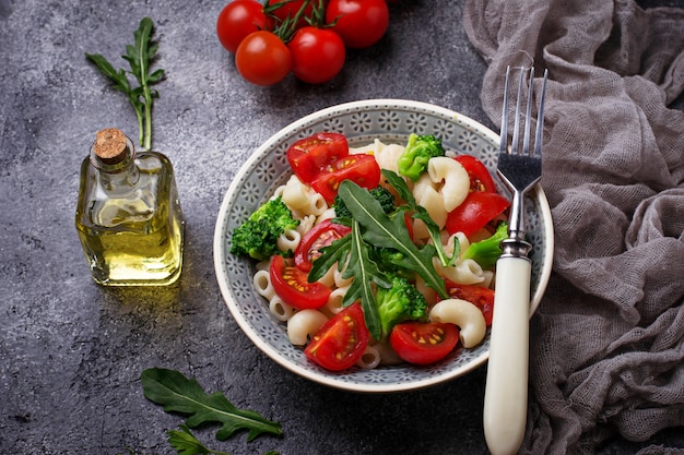 Salad with pasta, cherry tomatoes, broccoli and arugula. Vegan food