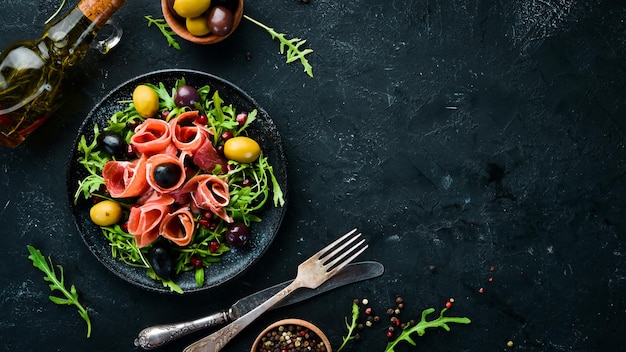 Salad with Prosciutto olives and arugula Cold snacks Top view Free space for your text